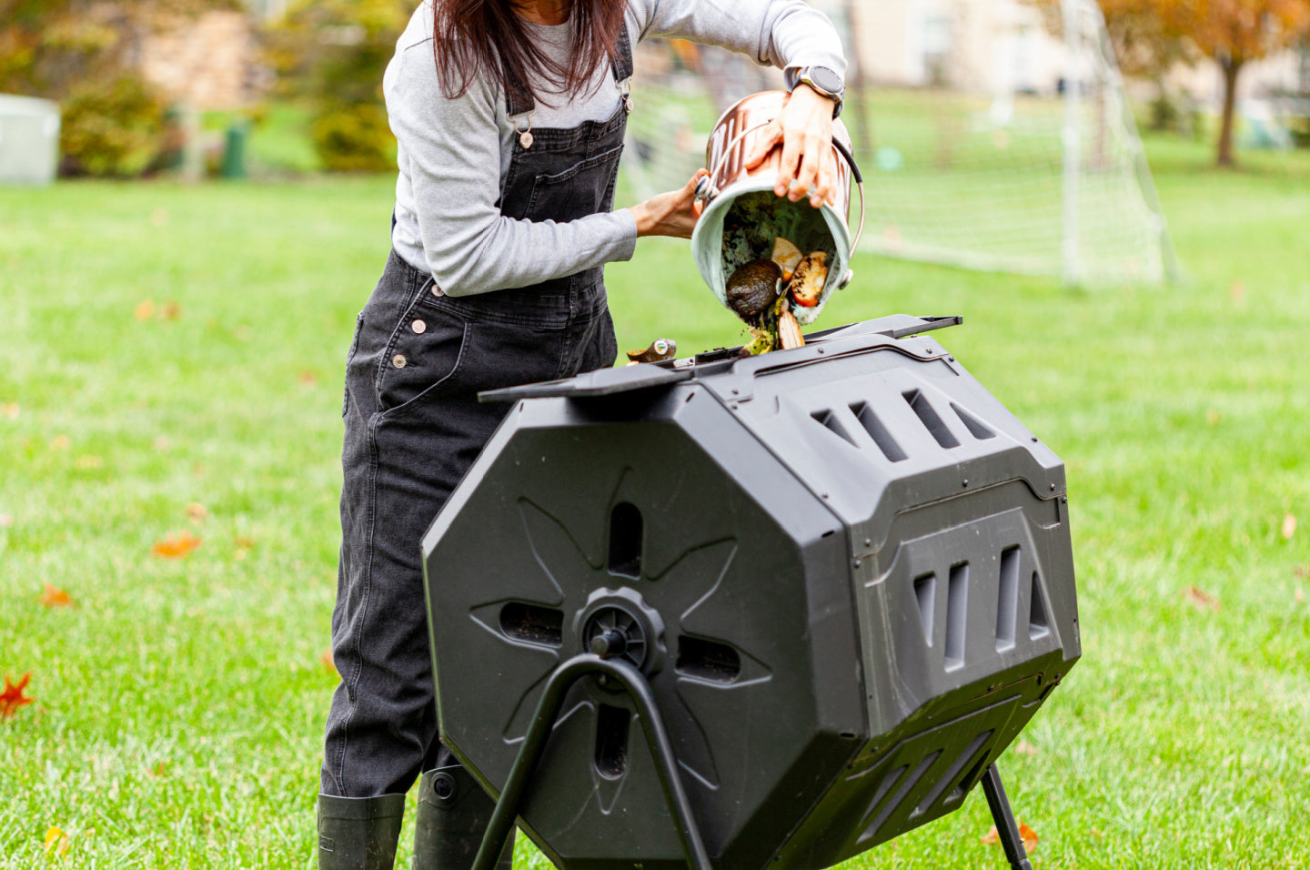 person loading scraps into a yard composter