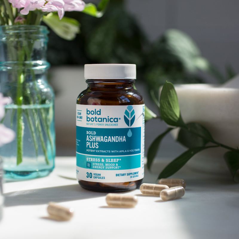 Bold Ashwagandha Plus bottle on a white table surrounded by flowers.